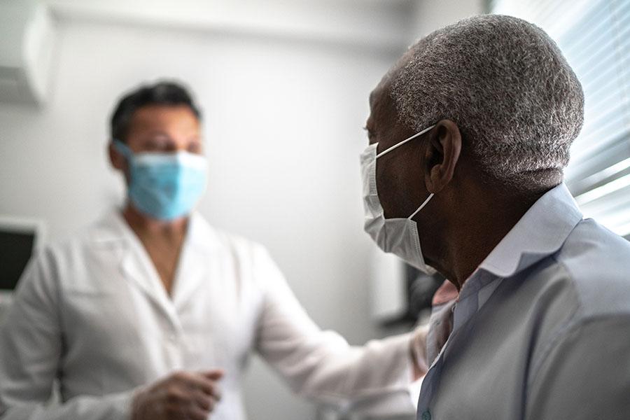 Doctor talking with patient at appointment while both wear masks