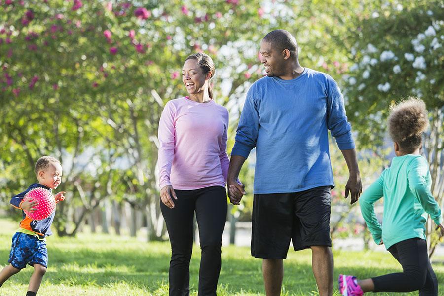 Two parents with their kids running around in the park