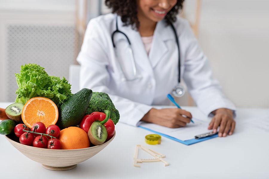 Doctor writing notes next to bowl of fruit