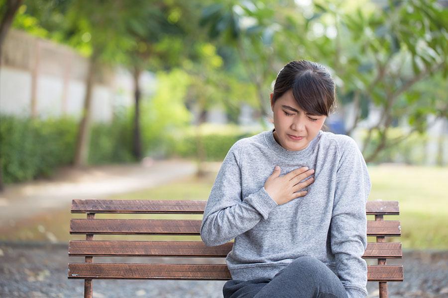 Woman holding chest, having heartburn